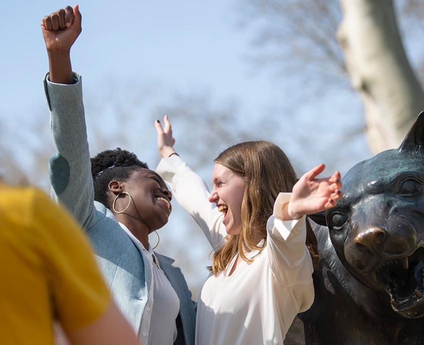 Two students hug next to a Panther statue