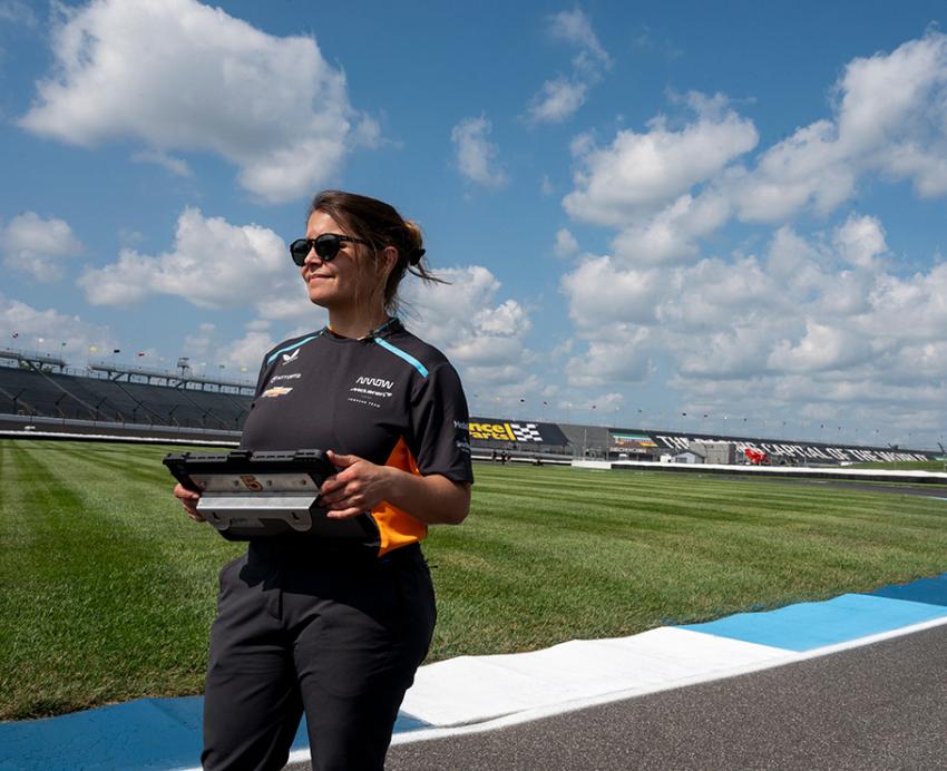 Gundlach holds a tablet while standing on a racetrack