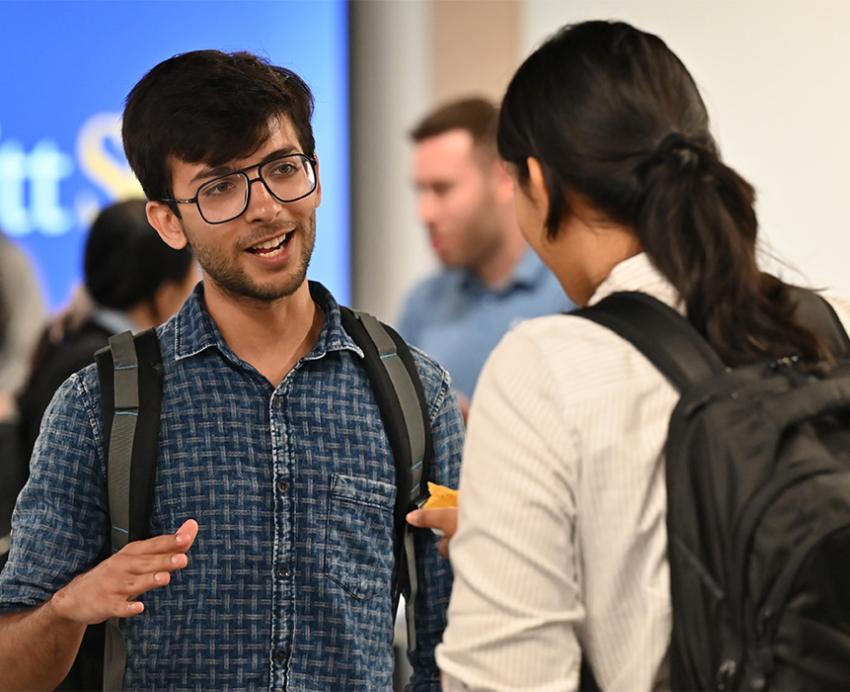 Two students talk at a School of Computing and Information event