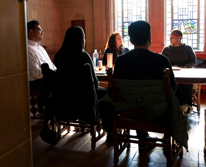 People sit around a table in a room with stained glass windows