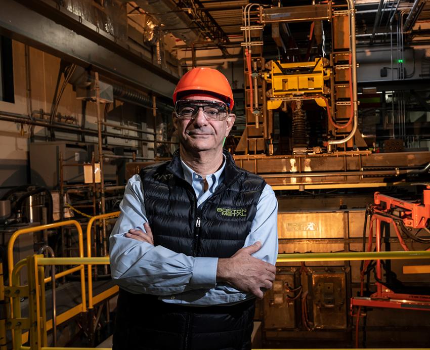 Carniero, wearing an orange hardhat, stands in an industrial factory