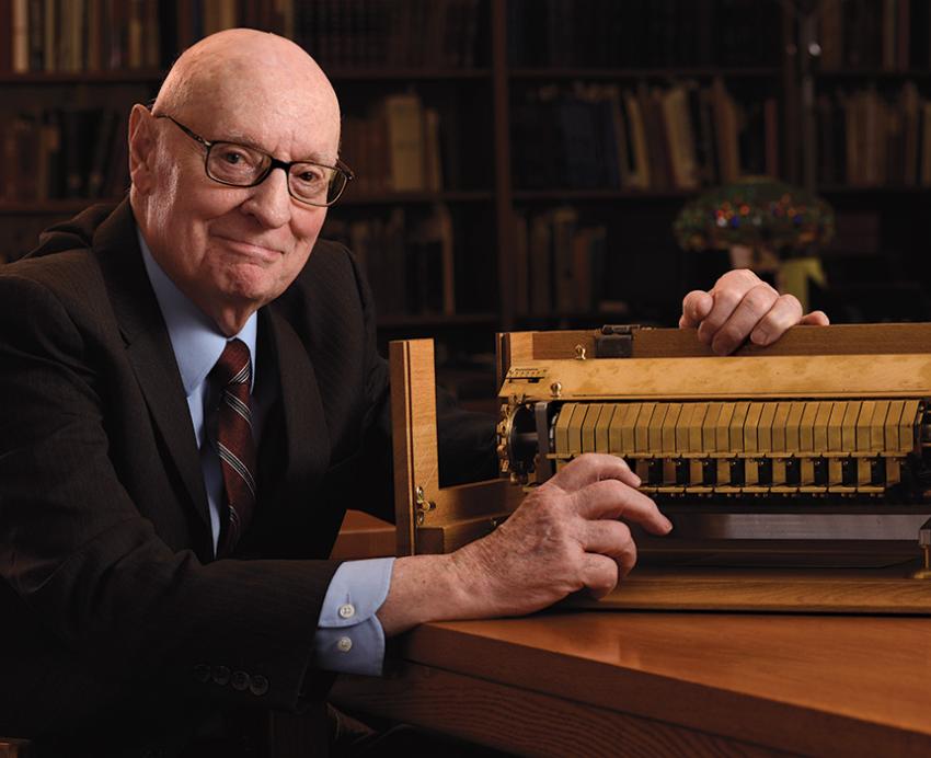 Rescher sits next to a gold cypher machine