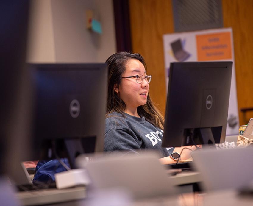A person sits in front of a monitor in a computer lab