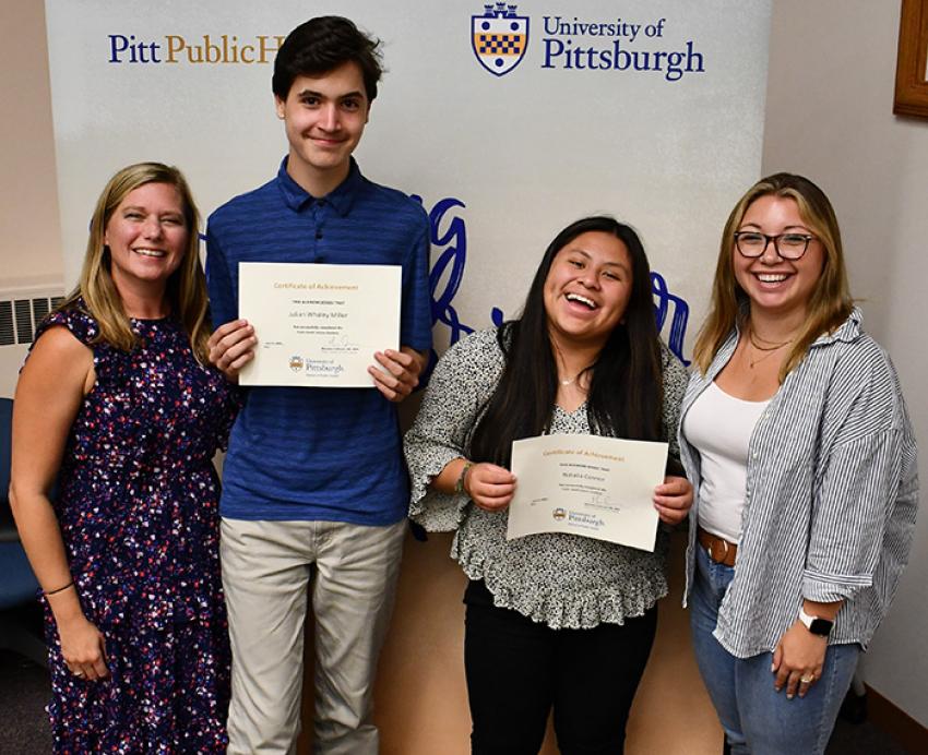 Two high school students hold certificates beside their mentors