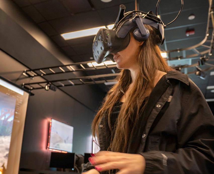 Synychych wears a VR headset to test her scuba diving application, displayed on a projector screen