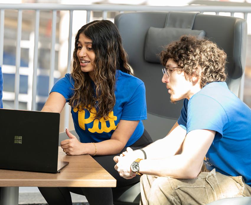 Four students huddle around a laptop