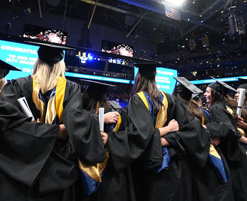 Graduates link arms after the ceremony