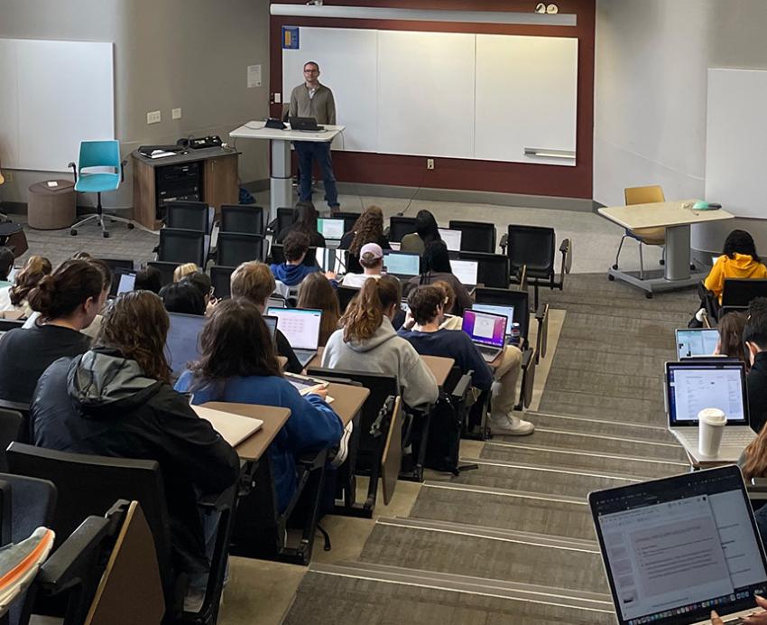 Students taking notes in a large lecture hall 