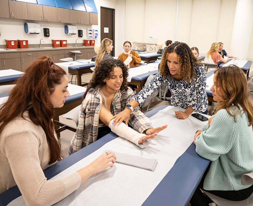 Students look at a practice splint as a professor talks
