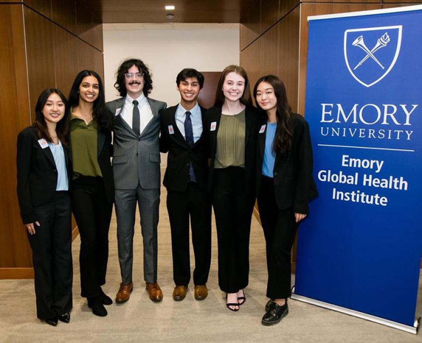 Six students stand beside an Emory University banner