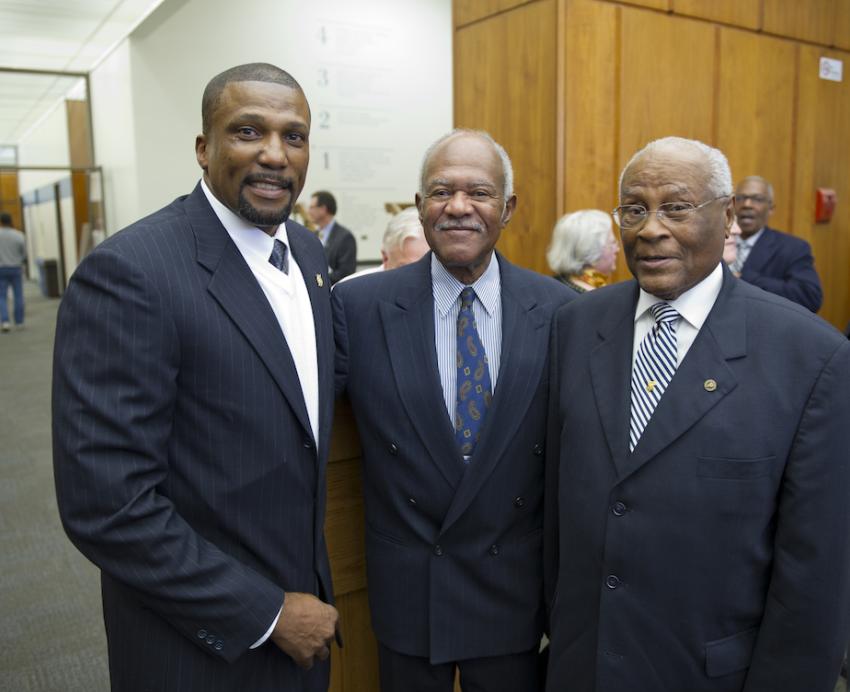 Three men in suits pose for the camera.