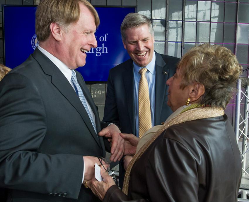 Chancellor Gallagher looks on as two people shake hands