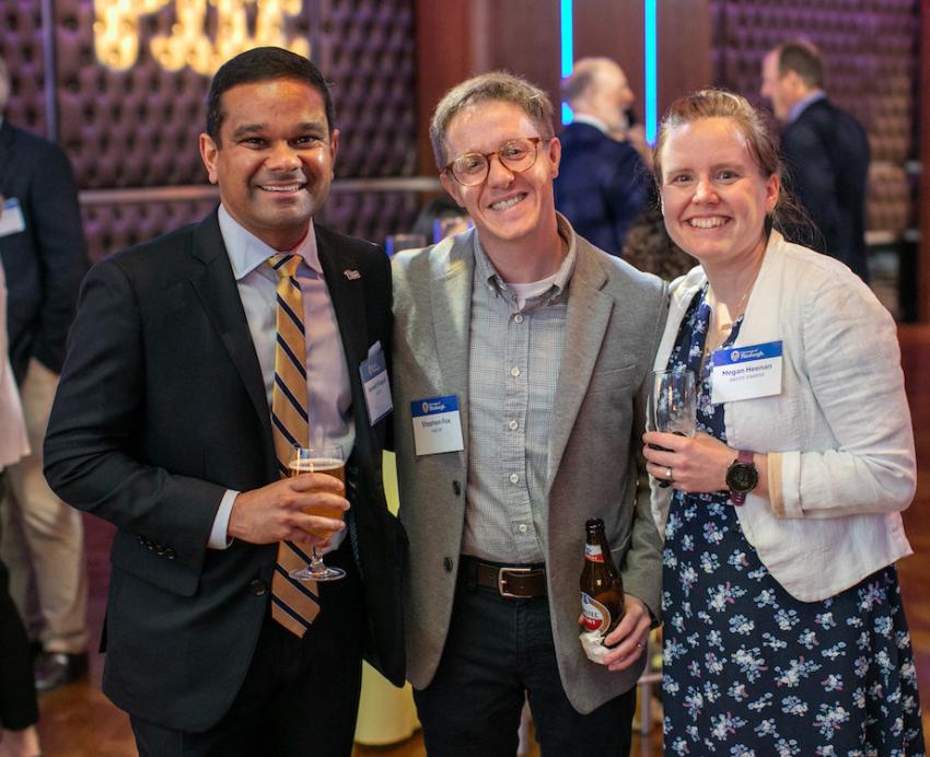 Three people hold drinks and smile.