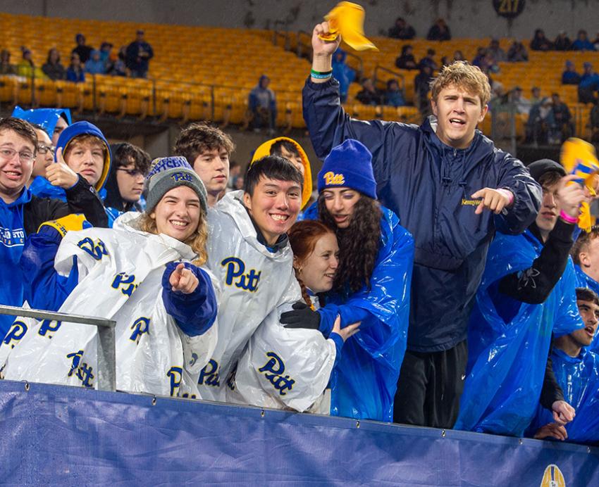 Students in Pitt gear cheer in stadium stands