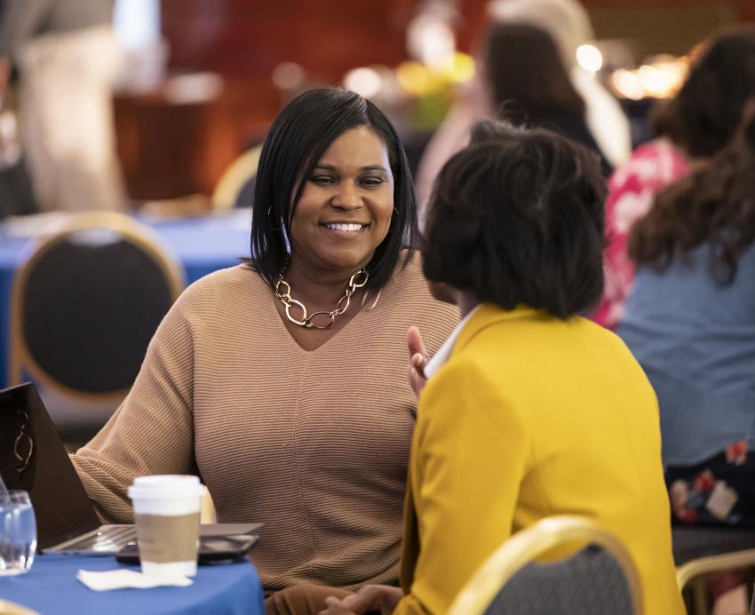A woman sitting at a table smiles to the person next to her.