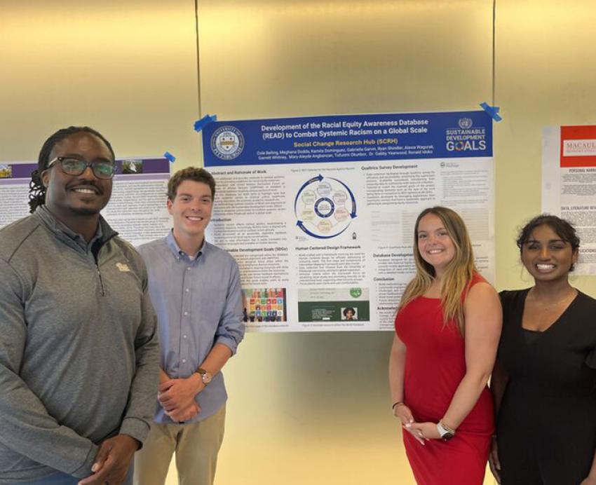 Ron Idoko and students stand around a research poster