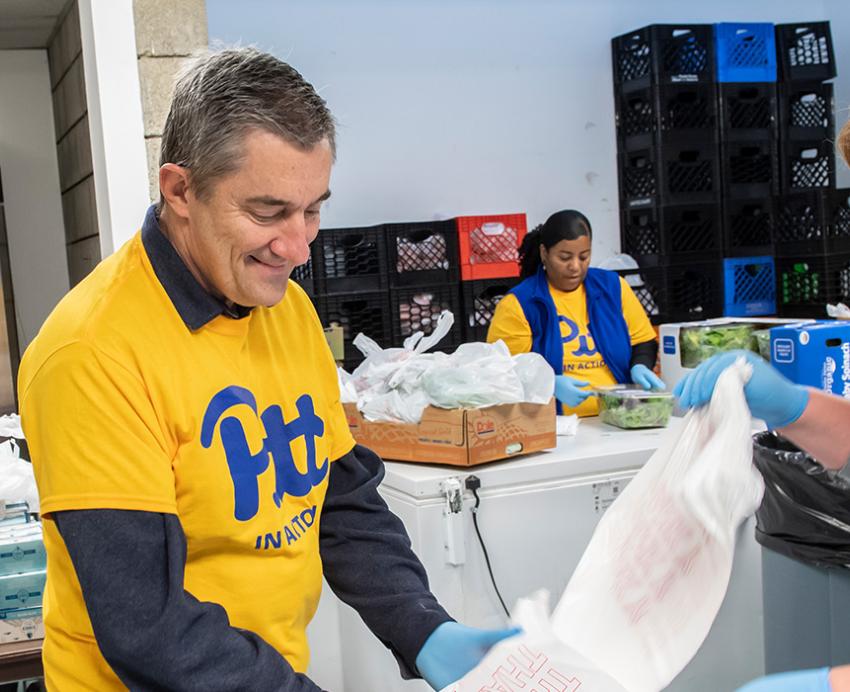 Volunteers wearing Pitt t-shirts pack bags of supplies