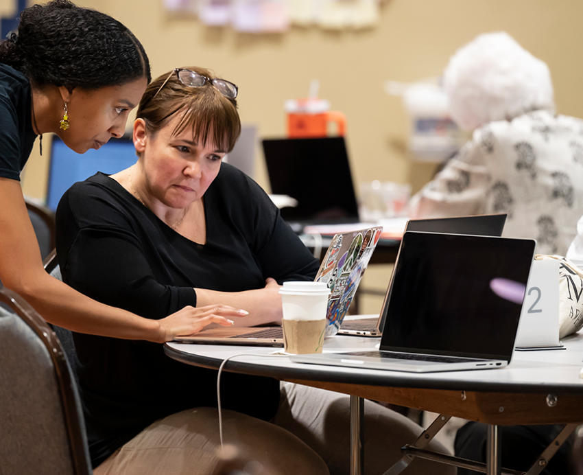 Two people looking at a computer during a RECI event