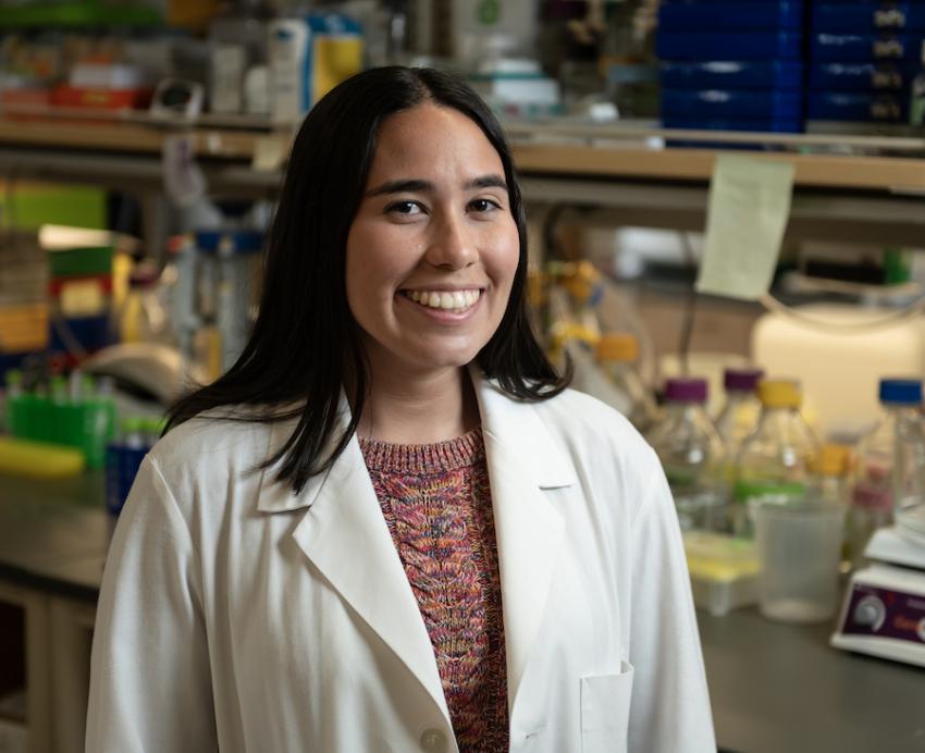 A woman wearing a lab coat smiles for camera.