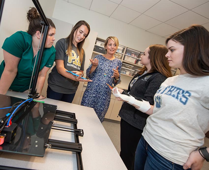 Students listen to an instructor explain a piece of technology