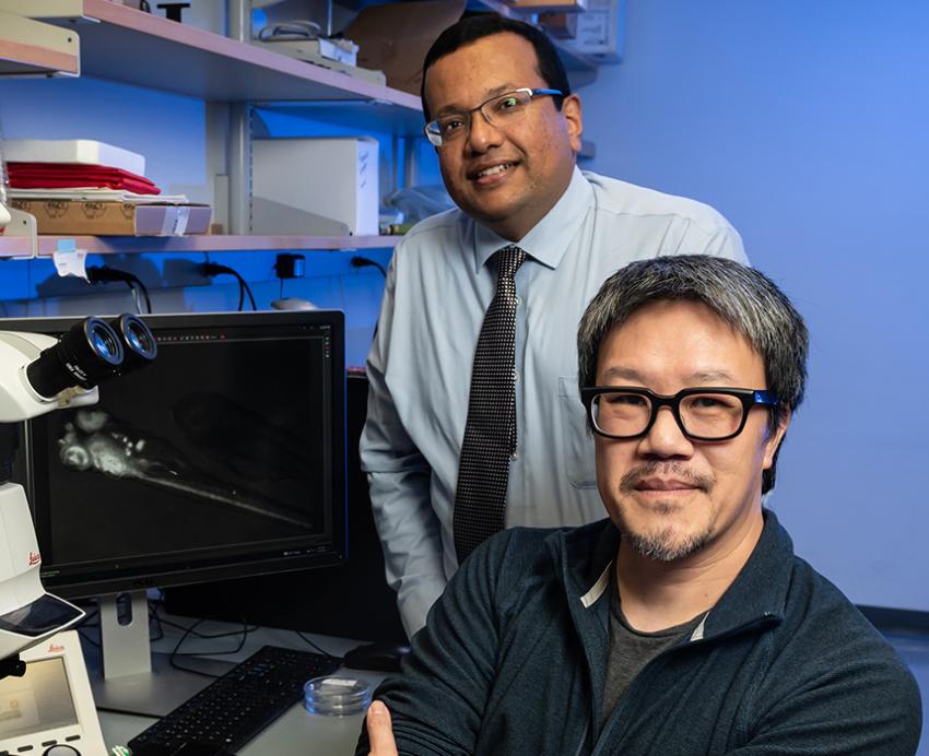Manush Saydmohammed and Michael Tsang with a microscope in the lab