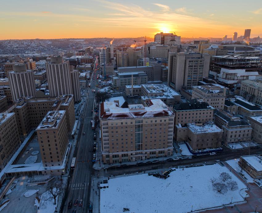 A snow-dusted campus is set against the backdrop of a sunset.
