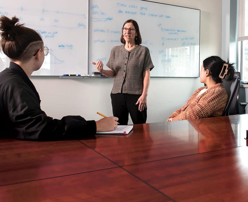 Maria Brooks talking to several people in front of a whiteboard