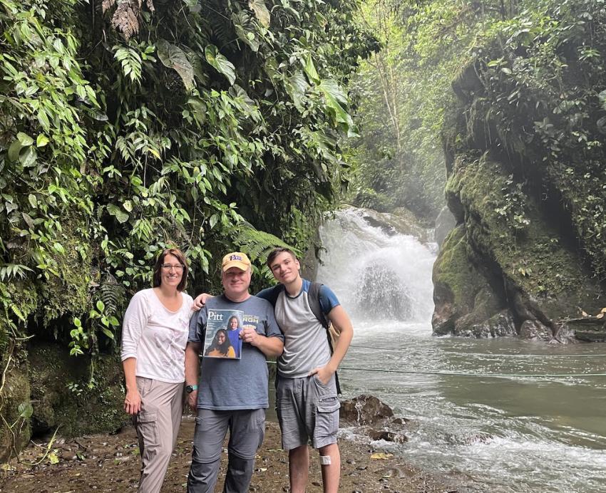 Three people standing in front of a waterfall