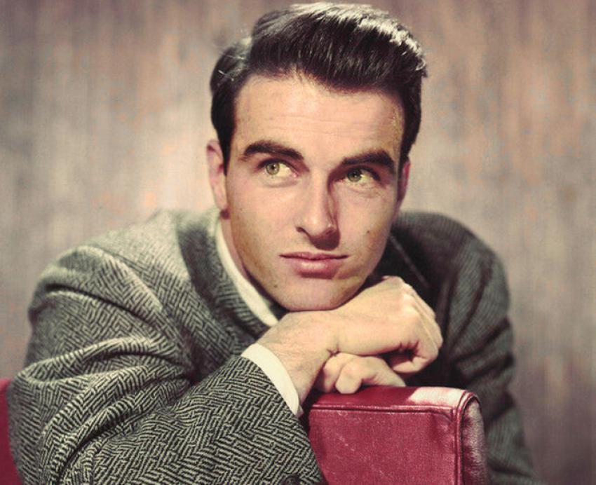 Montgomery Clift leans on a red suitcase