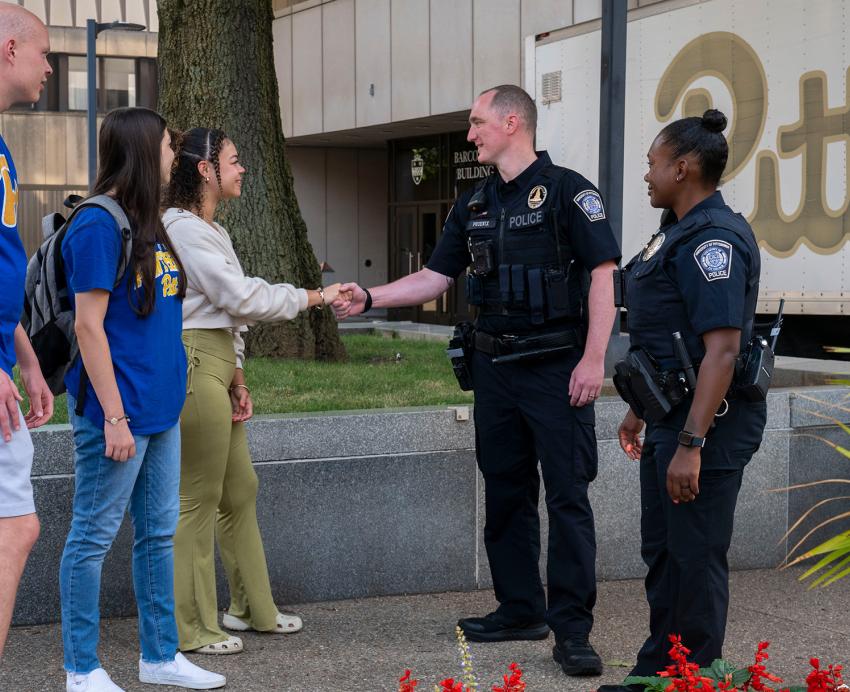 Public Safety police officer speak with and shake the hands of students.