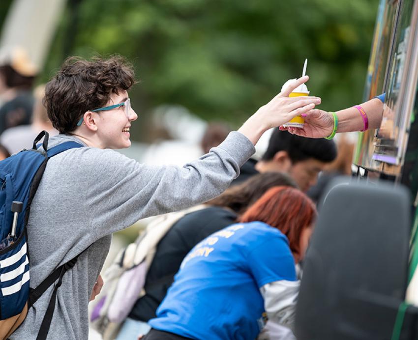 Smiling student receiving food from a food truck.