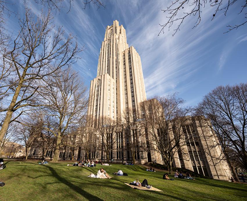 Cathedral of Learning in early spring, with students lounging on the green