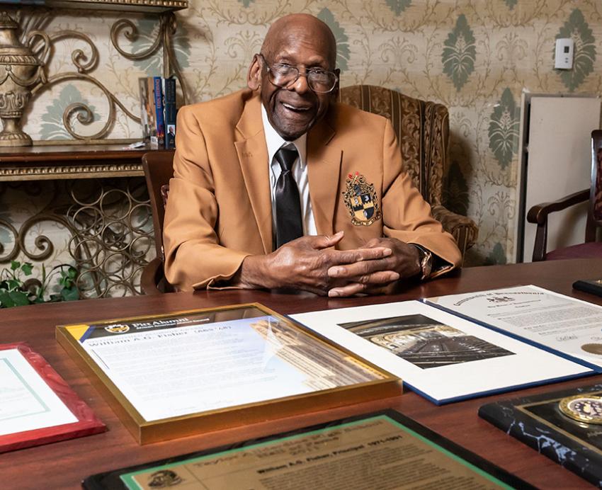 Fisher sits at a table, his awards spread before him.