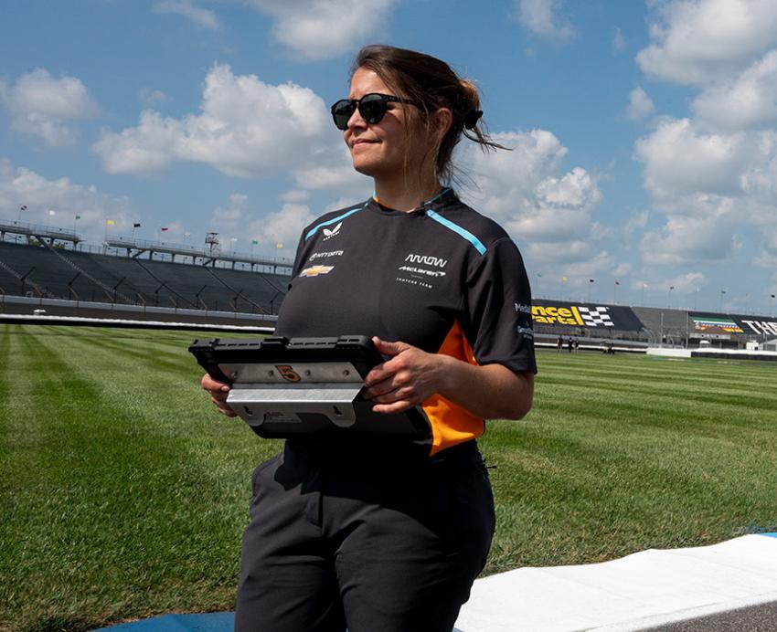 Kate Gundlach stands on a racing car track on a lightly cloudy day