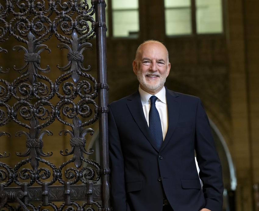 Man in suit smiling while standing near gate