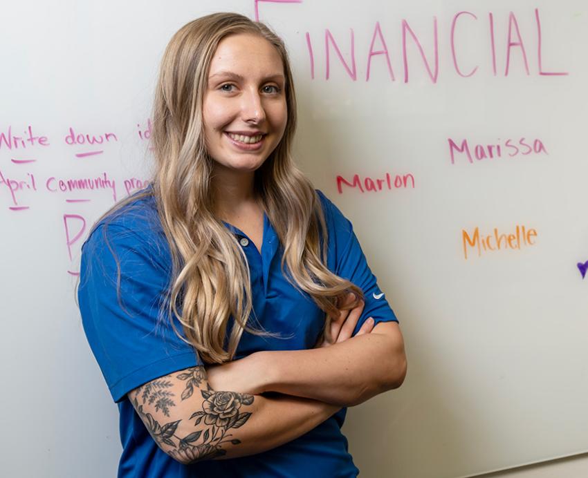Michelle Kingsley in front of a whiteboard reading "Financial Wellness Center"
