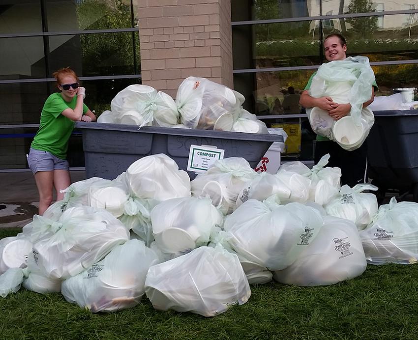 Two students posing with garbage bags