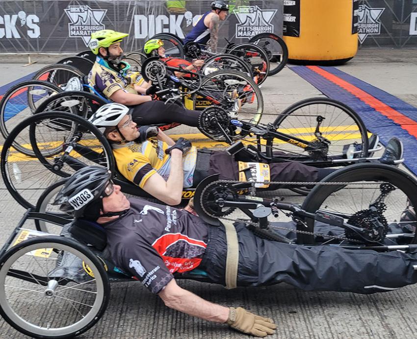 Hand cyclists line up in a row at the marathon starting line.