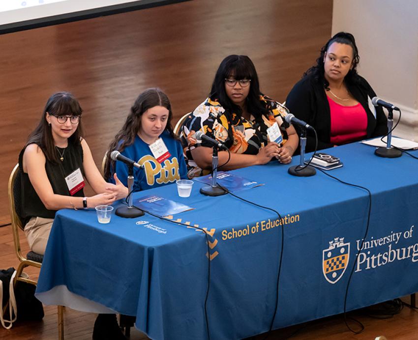 Students sit at a table as part of a panel