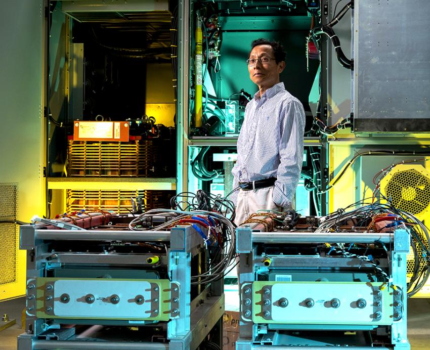 A researcher stands amid electrical engineering equipment in a well-appointed lab space.