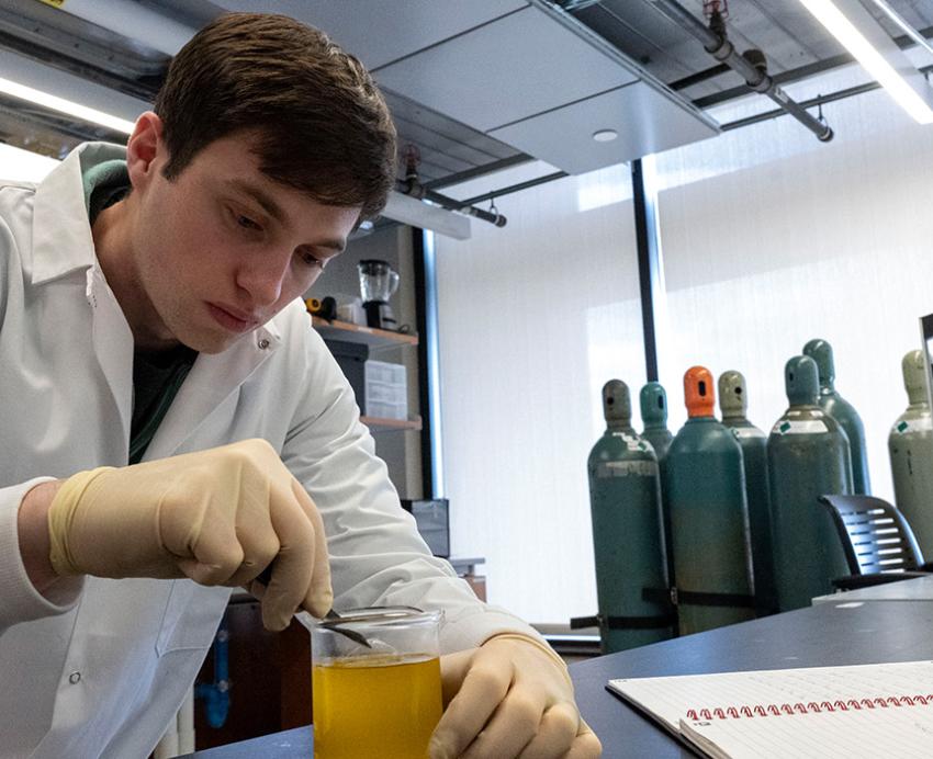 A student stirs a beaker in a lab.