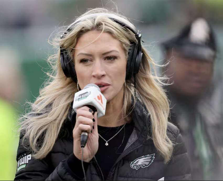 A woman holding a microphone provides a report during a professional football game
