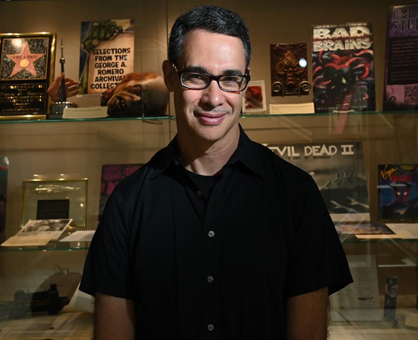 Adam Lowenstein in front of a display showcasing horror films