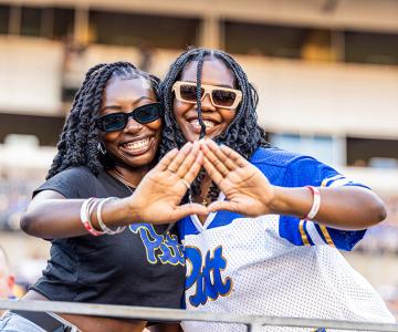 Two smiling women putting their hands together into a triangle