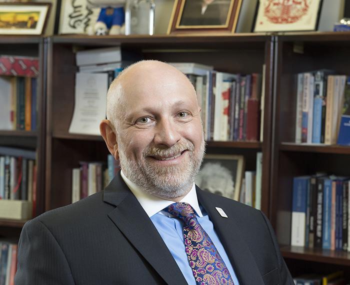 Ariel Armony smiling, book shelves in background