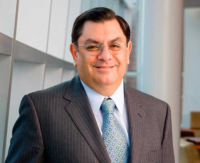 Arjang Assad wearing grey suit and glasses, smiling