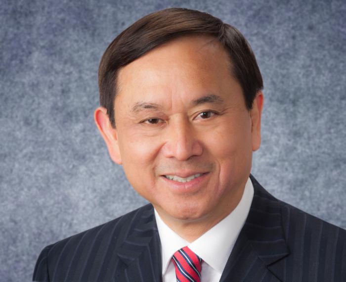 Freddie Fu smiling in black suit with red tie