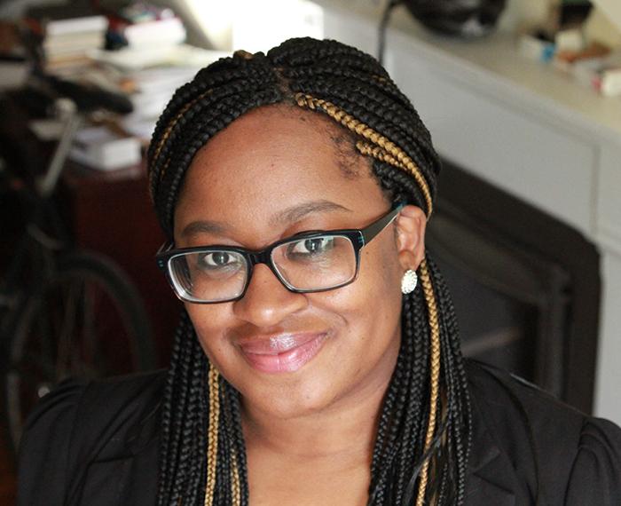 Keisha Blain smiling, wearing glasses with earrings and black shirt