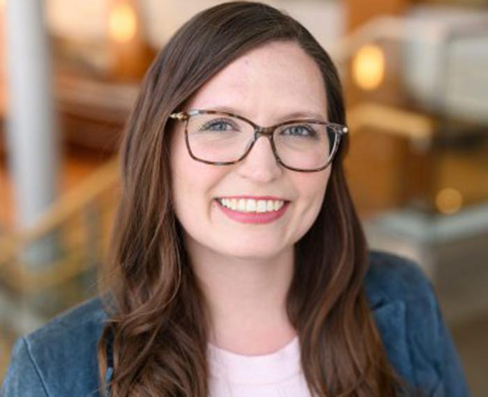 Jessica Thompson smiling with glasses and blue jacket