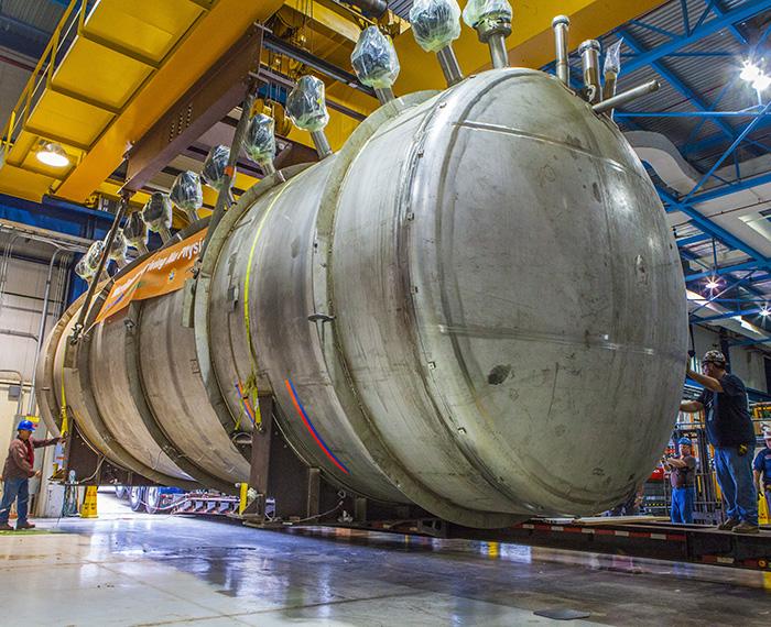 Large metal reactor with several people working around it.